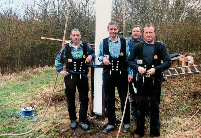 Vier Zimmerer der Gebrüder Bies in Zunftkleidung beim Aufrichten